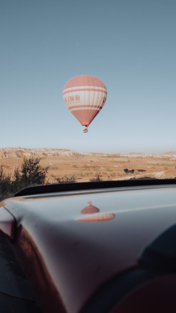 A hot air balloon soars above the unique landscape of Göreme, Turkey, during a clear day.